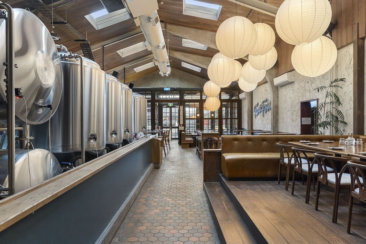 Brewery interior with stainless fermentation tanks, timber ceiling and pendant lights