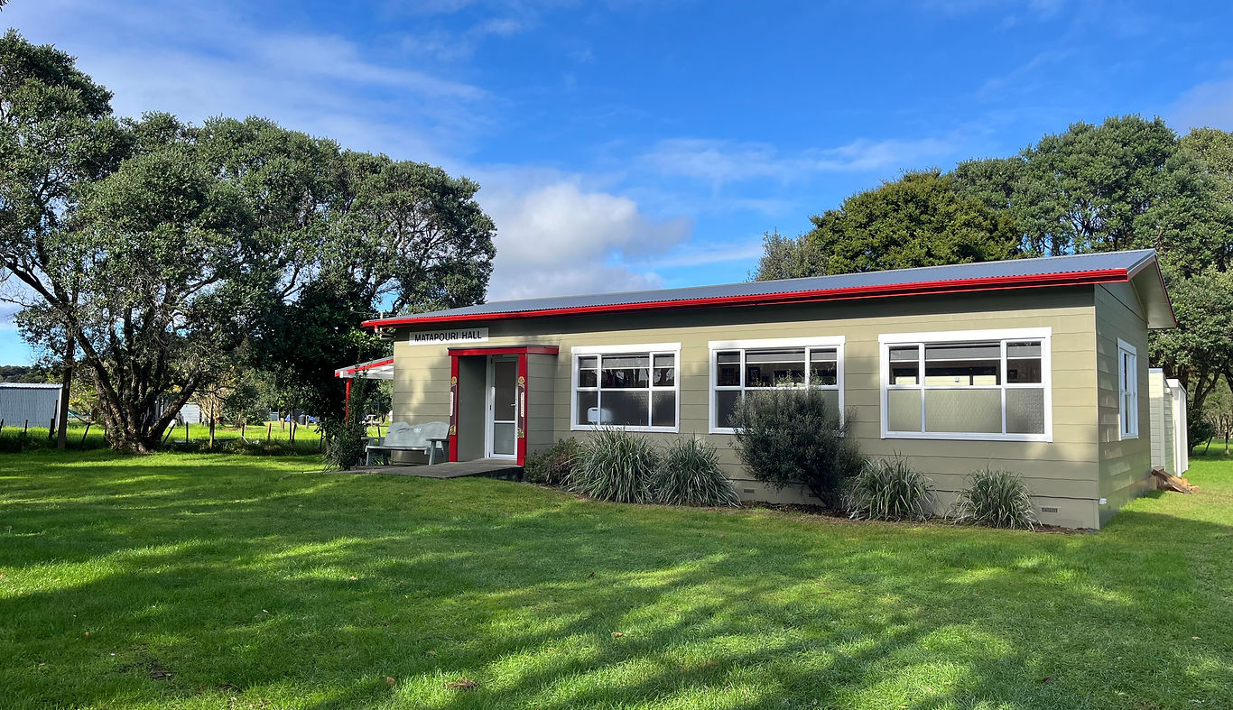 Small rural hall with green cladding, red roof trim, and lawn surrounds