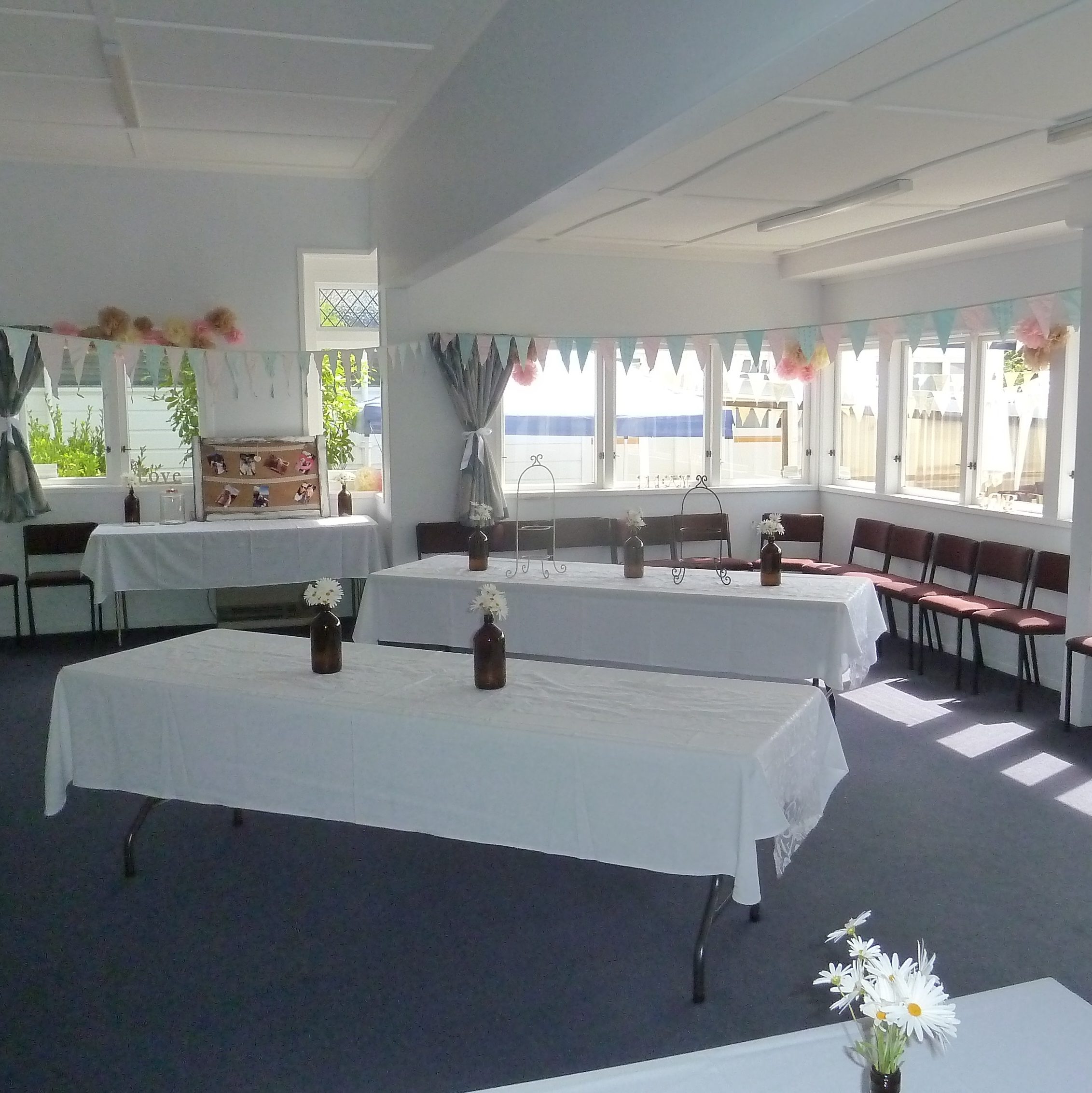 Hall room set up for a function with trestle tables, white cloths, bunting and decorations