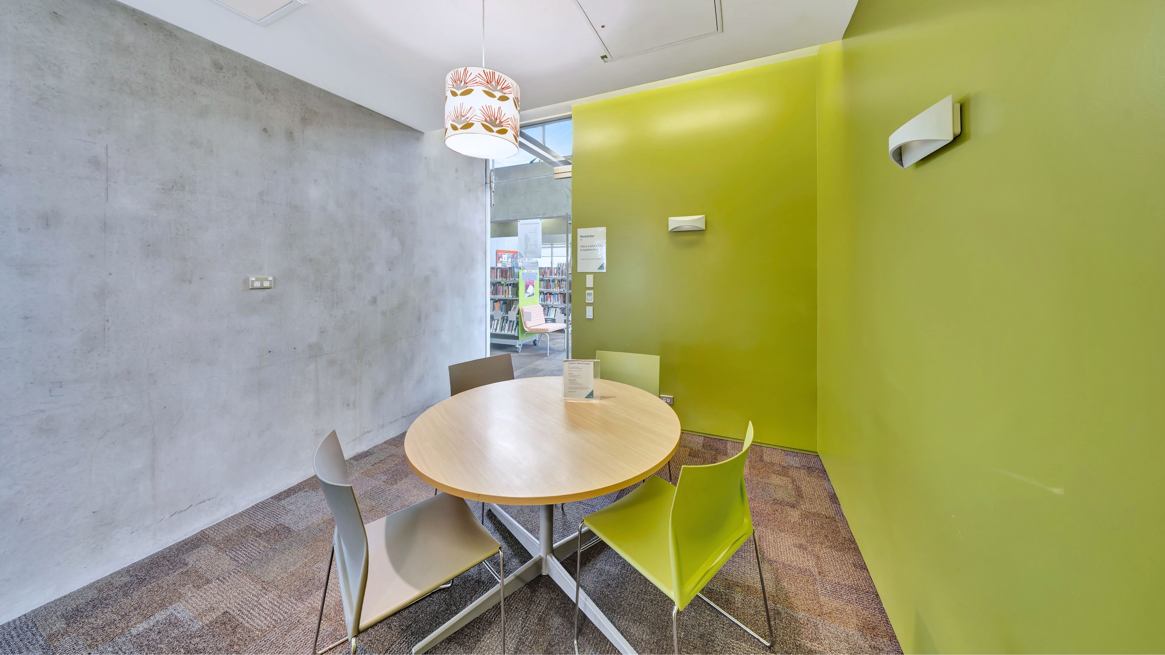 Small meeting room with round table, lime-green accent wall and pendant light