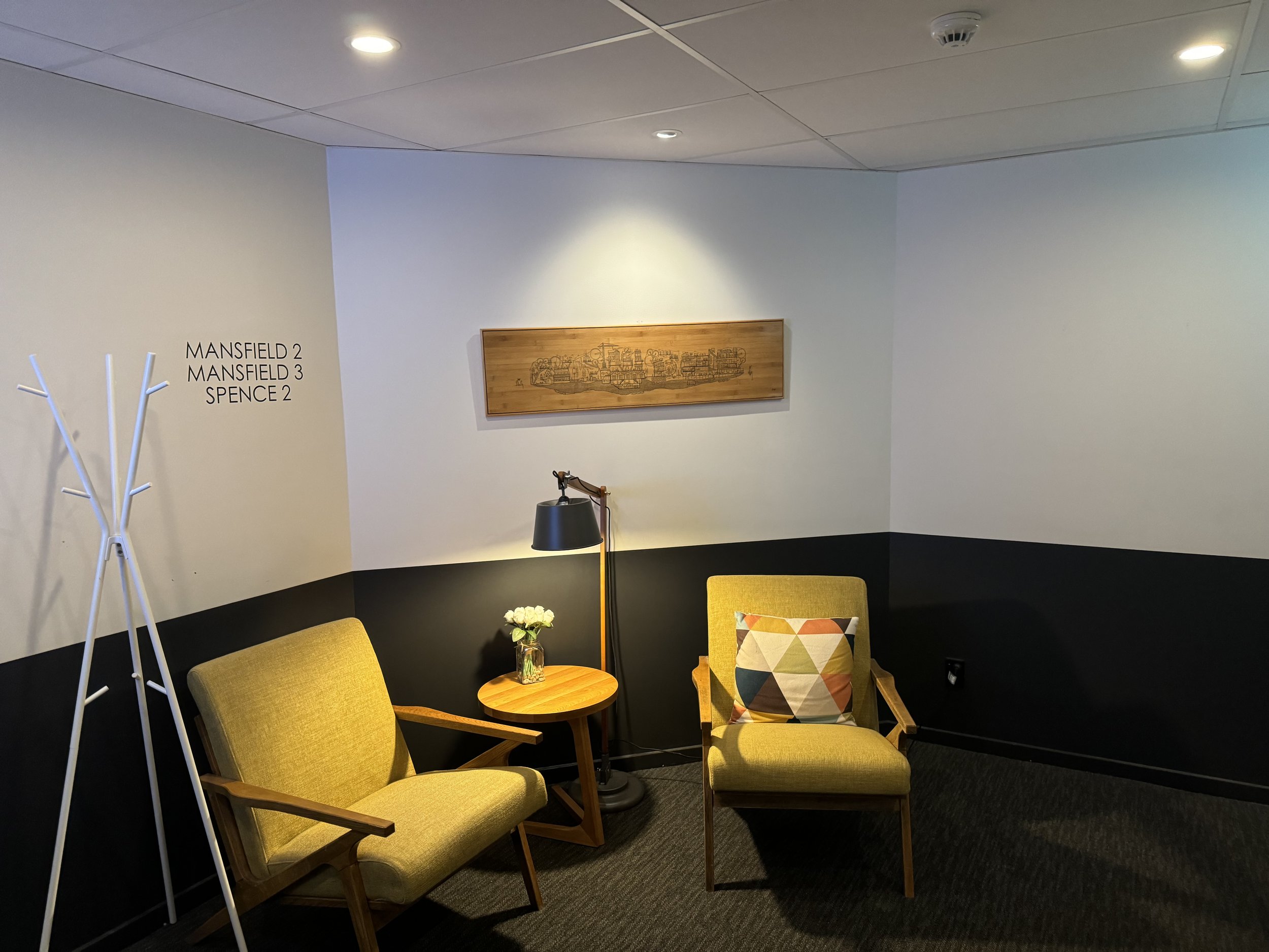 Small hotel lobby lounge area with two yellow armchairs and artwork