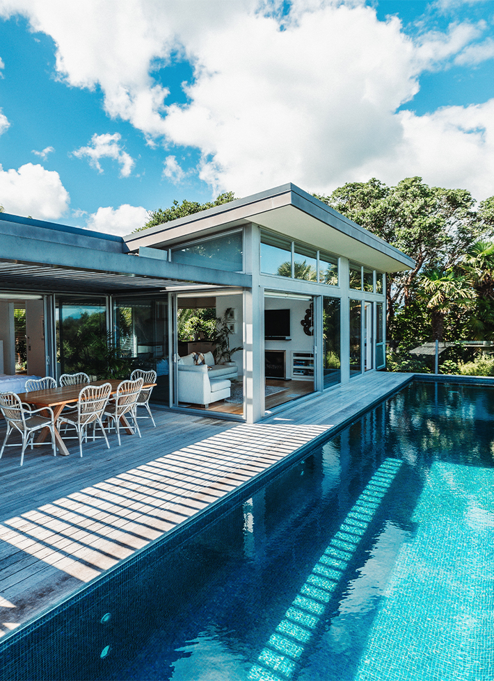 Modern lodge exterior with infinity pool and deck sun loungers