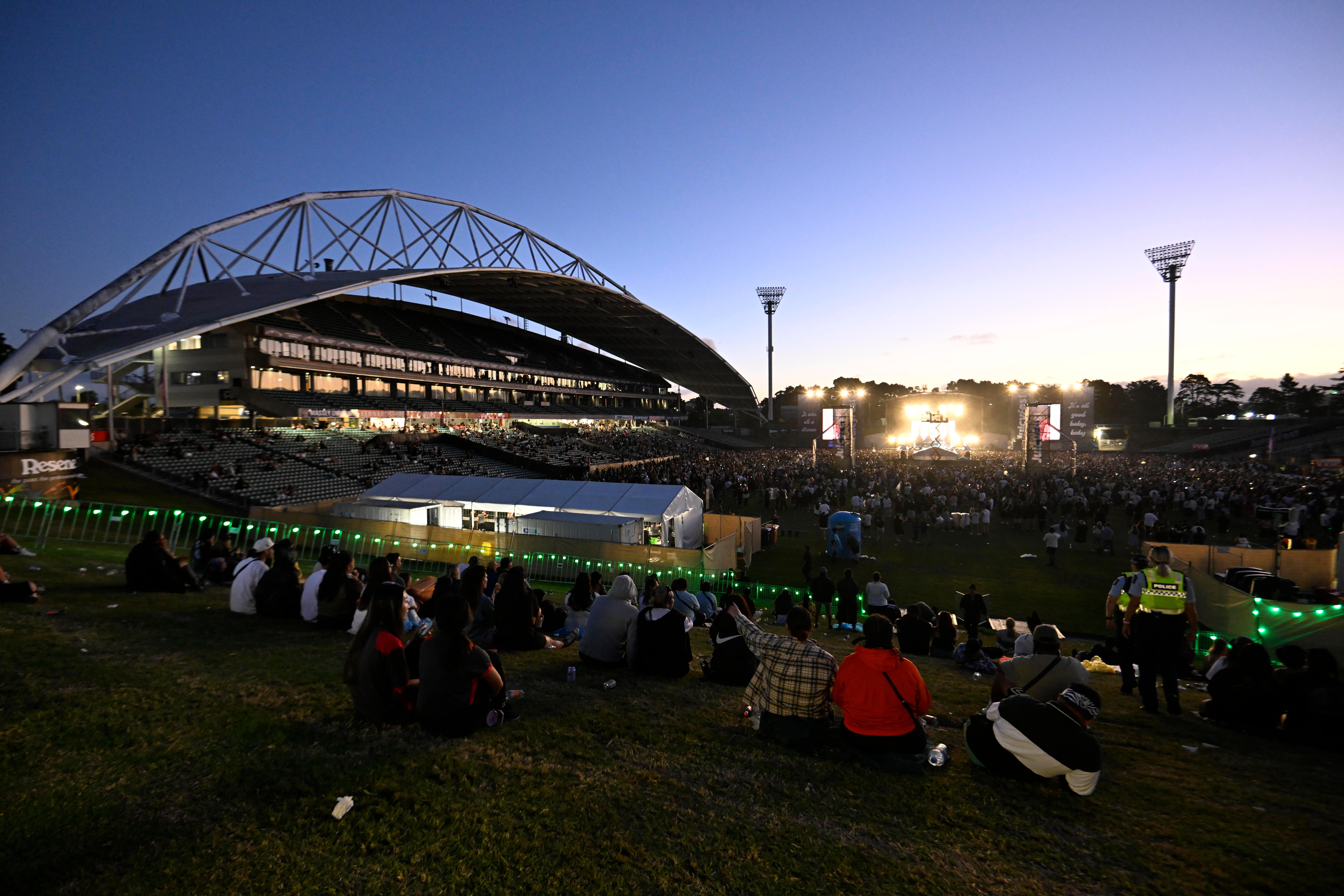 Stadium exterior at dusk with large crowd and concert stage inside