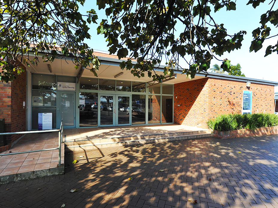 Single-storey brick and glass community building with paved forecourt