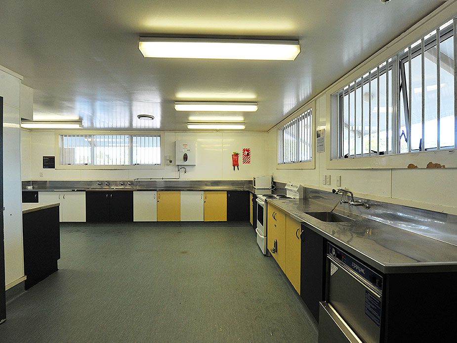 Commercial kitchen with yellow and black cabinets and stainless steel benches
