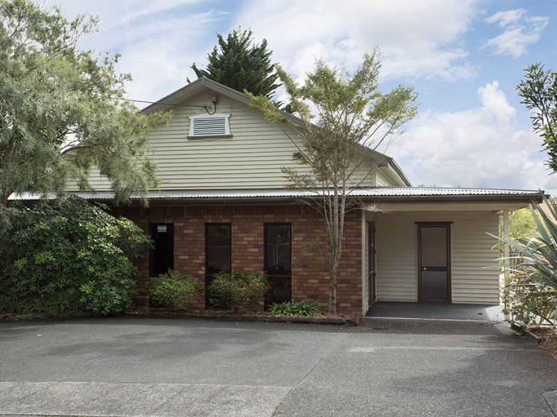 Cream weatherboard hall with gabled roof, brick lower section, metal roof, trees alongside
