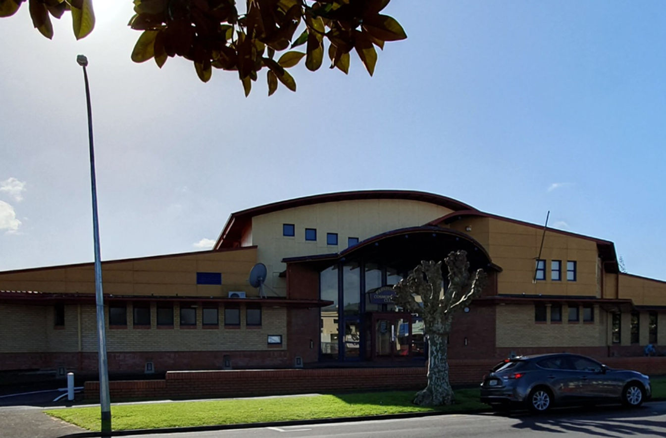 Large club building exterior with curved roof and entrance canopy