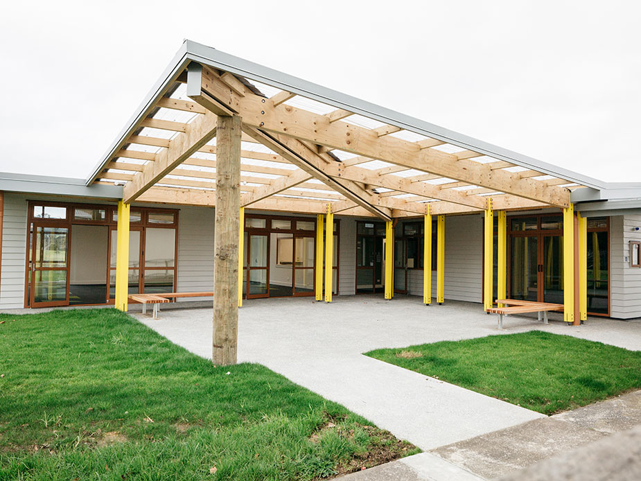 Modern single-storey community hub with timber pergola and yellow-painted columns
