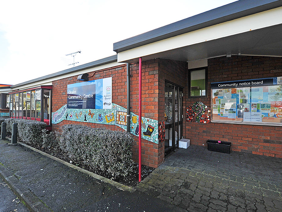 Single-storey brick community centre entrance with mosaic artwork and notice board