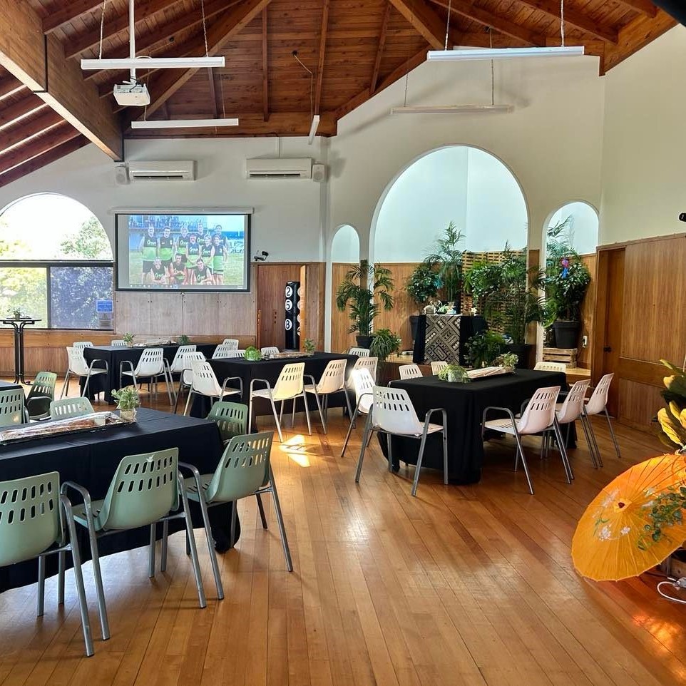 Hall with timber vaulted ceiling, arched windows, tables set with black cloths