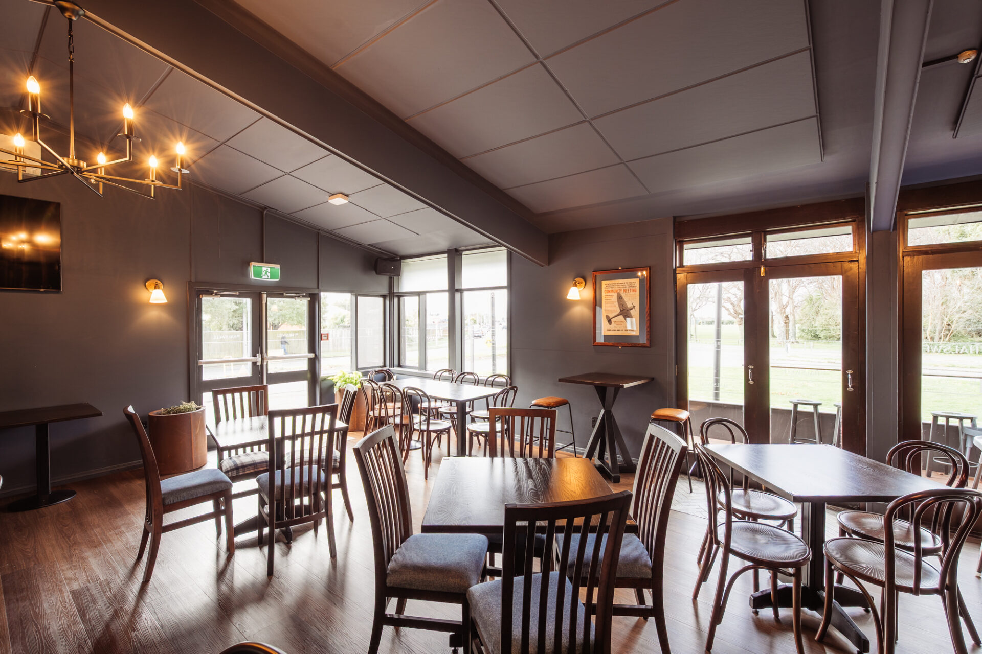 Pub dining room with dark walls, timber chairs and natural light from large windows