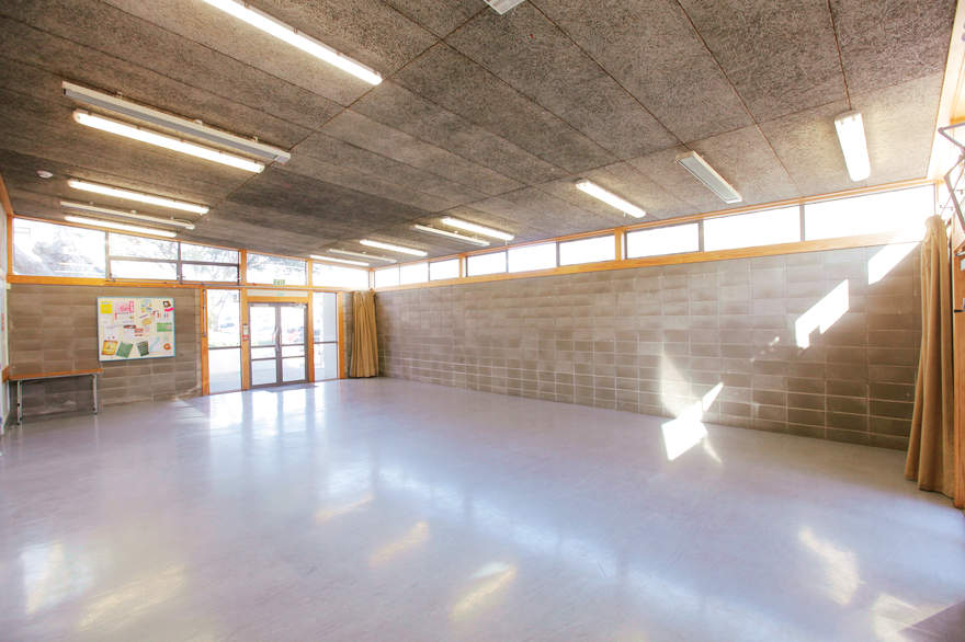 Plain hall with block walls, high clerestory windows and polished floor