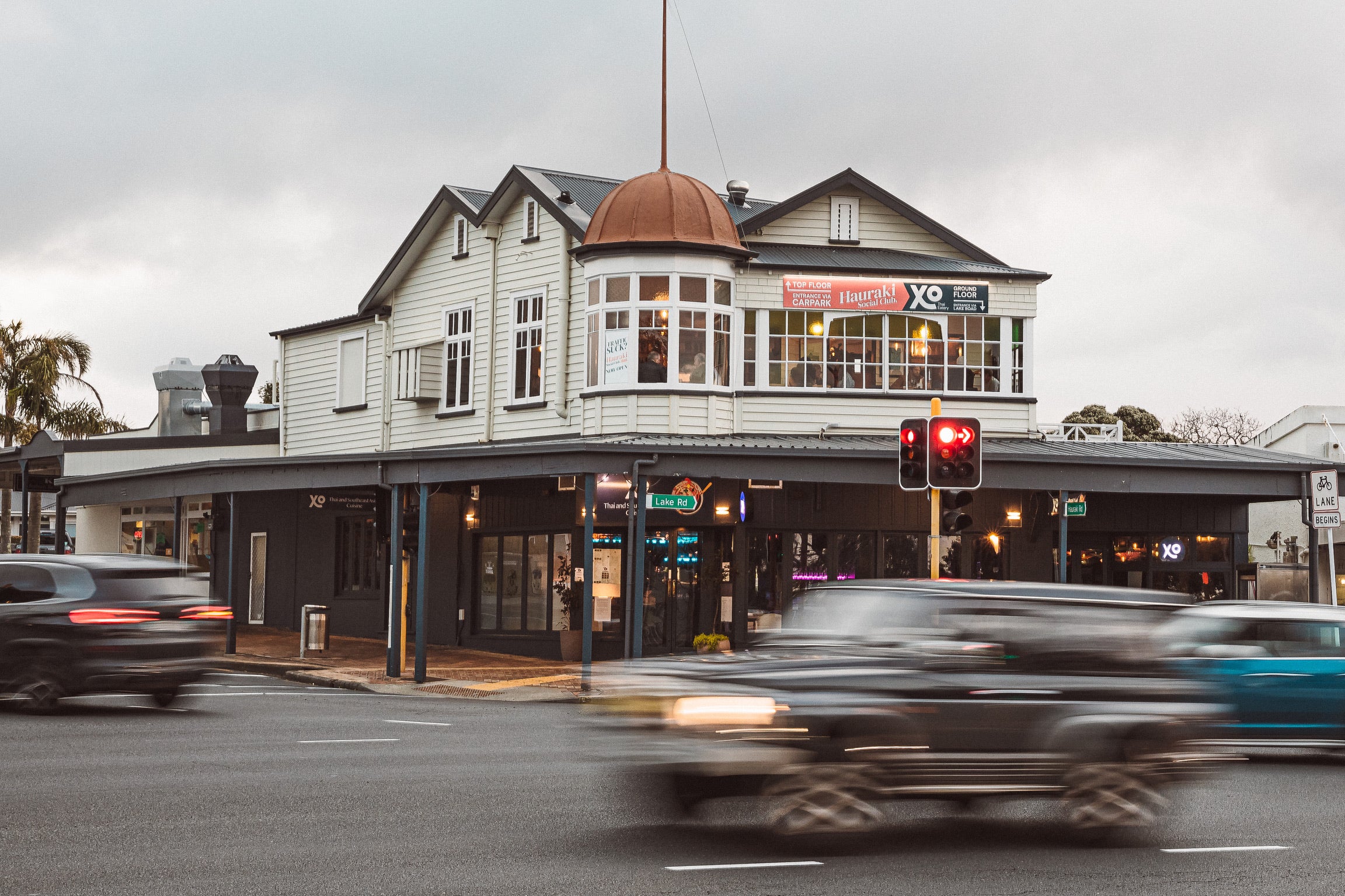 Historic two-storey white timber building on a street corner with copper dome detail