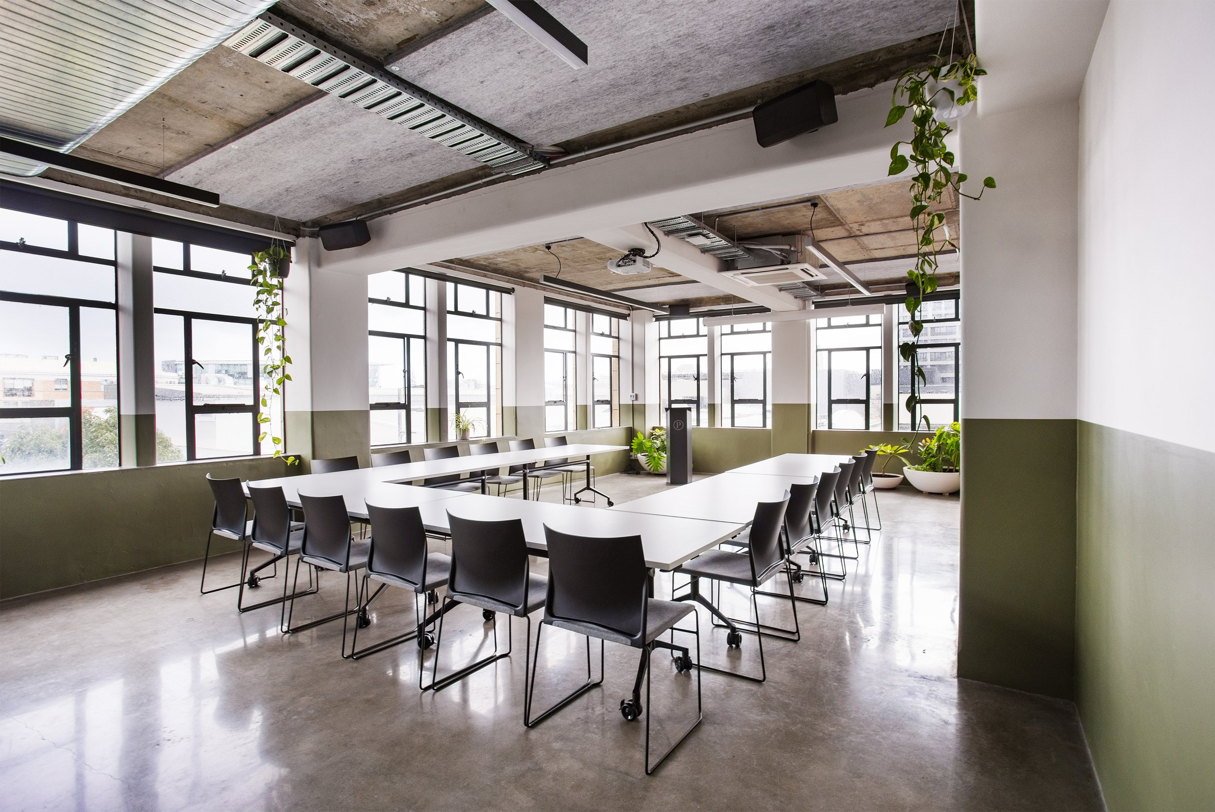 Conference room with U-shaped table layout, exposed concrete ceiling and large windows