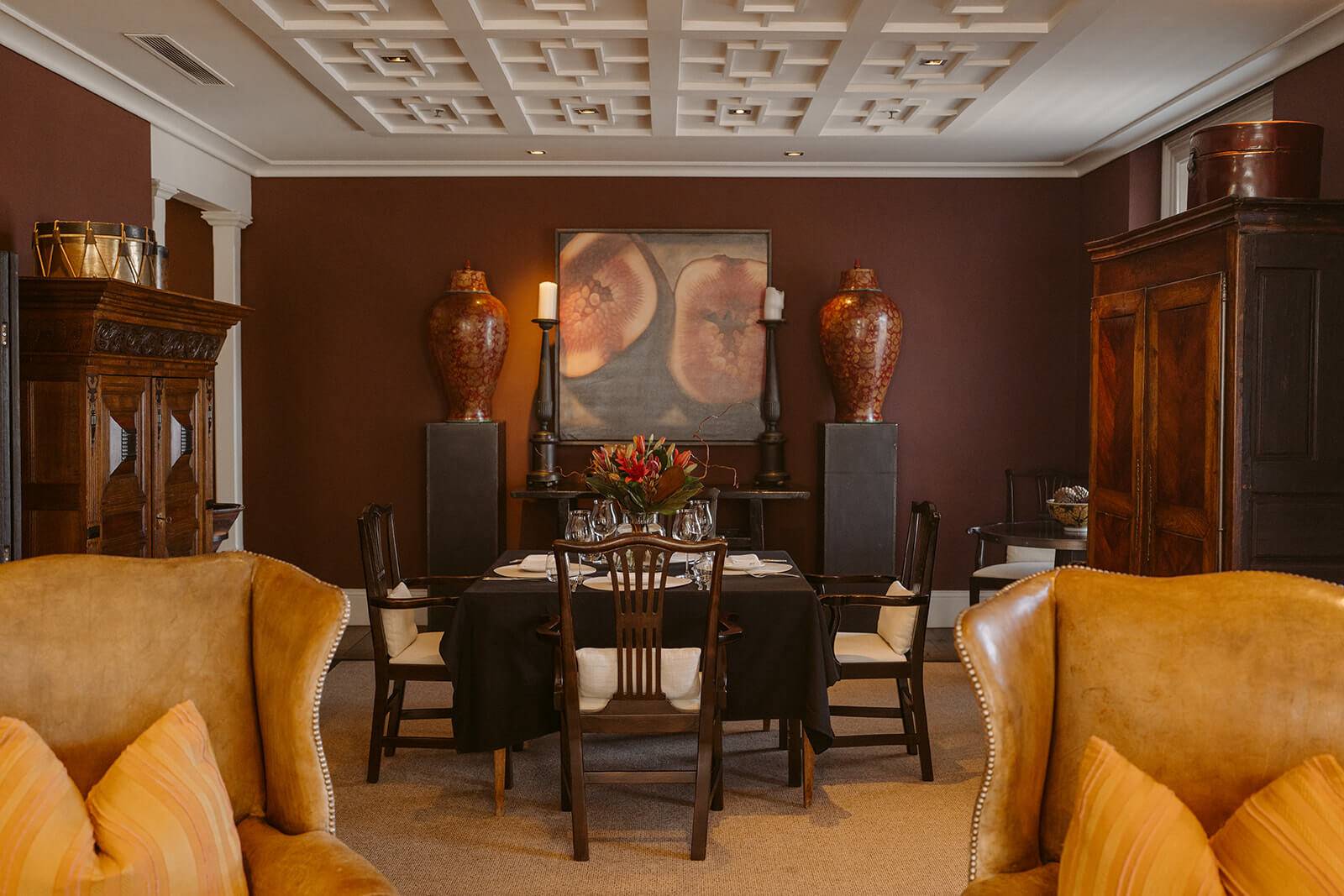 A private room with deep burgundy walls, coffered ceiling and antique furniture