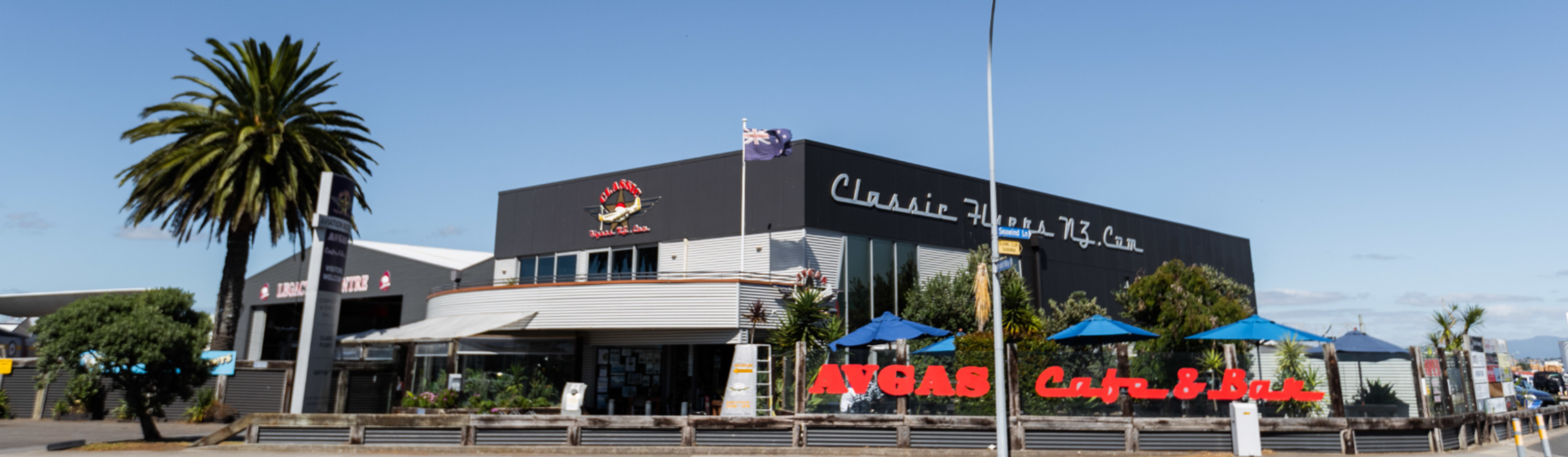 Classic Flyers NZ building exterior with cafe signage and palm trees