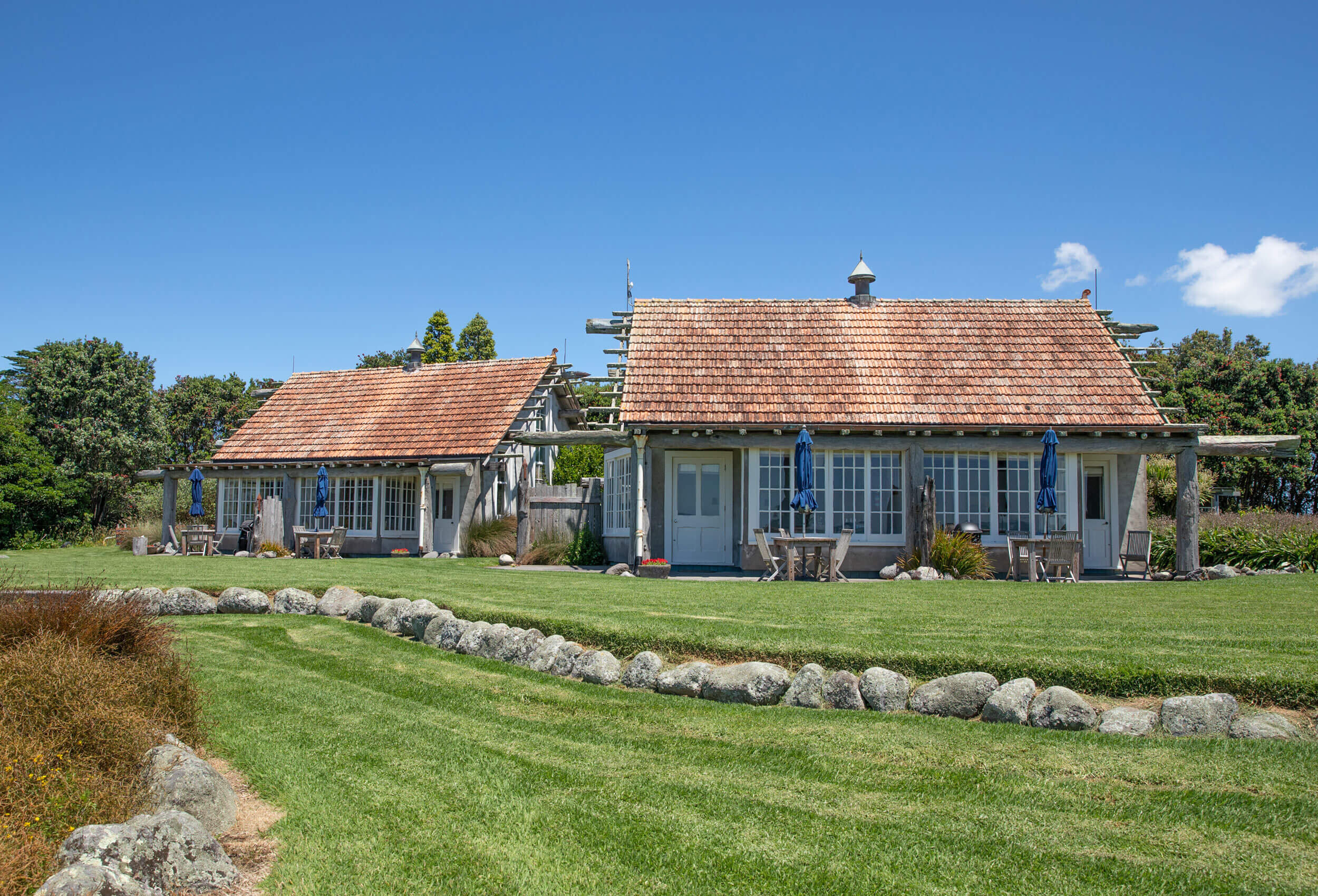 Low timber and stone villa buildings with cedar shingle roof on green lawn