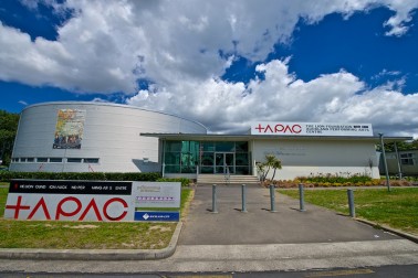 Performing arts centre exterior with cylindrical curved facade and centre signage under blue sky