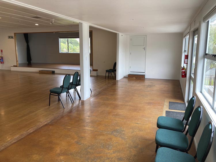 Empty community hall with concrete floor, columns and windows