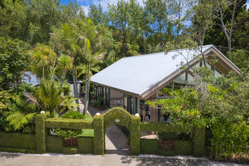 Timber and glass pavilion building surrounded by native plantings
