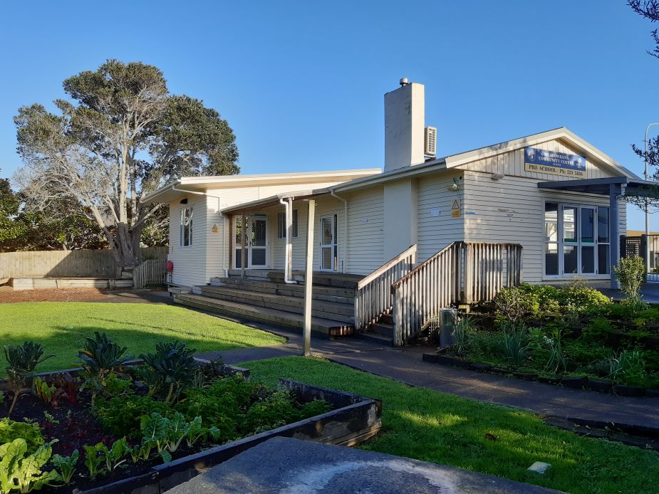 Single-storey community centre exterior with garden beds and entrance steps