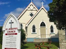 Small white wooden church with Gothic windows and sign