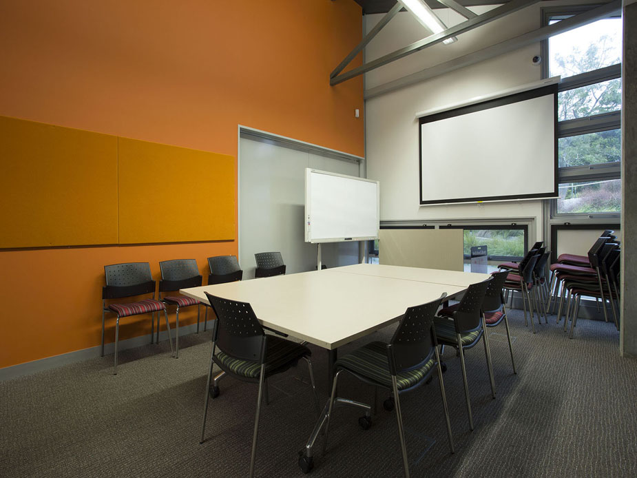 Meeting room with orange accent wall, table and projection screen
