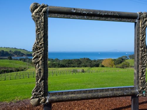 Decorative frame overlooking coastal fields and sea at Shakespear Regional Park