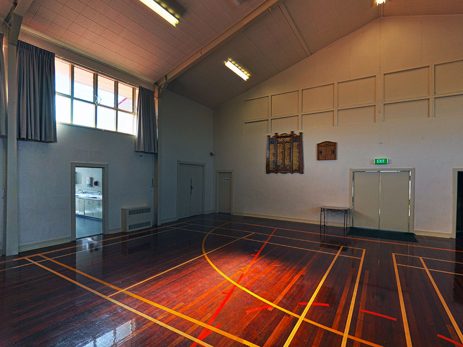 Hall interior with polished timber sports floor, high windows and wall plaques