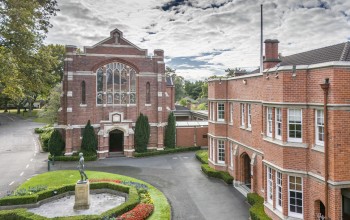 Red brick buildings with a chapel, arched entry, and landscaped grounds