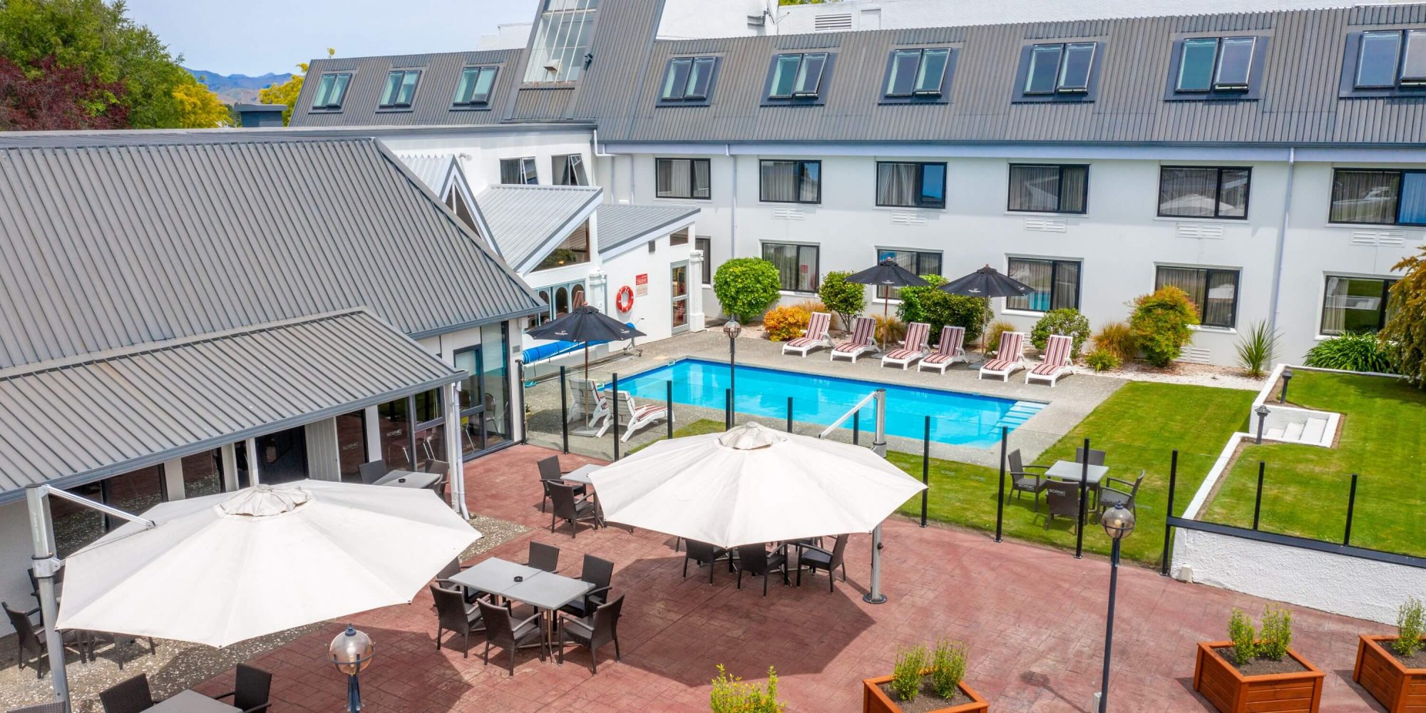 Hotel courtyard with outdoor pool, sun loungers, umbrellas and multi-storey building
