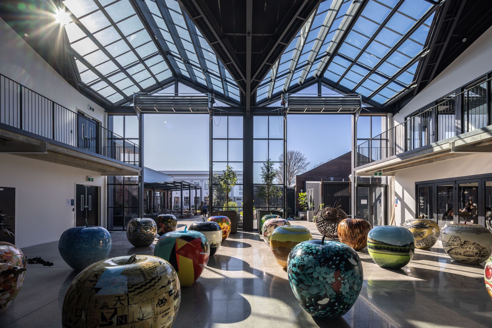 Interior atrium showing large apple sculptures, black spiral staircase and glazed roof