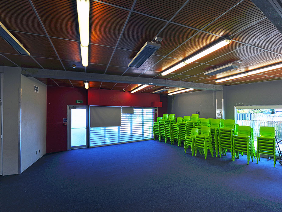 Hall with timber panelled ceiling, red accent wall and stacked green chairs