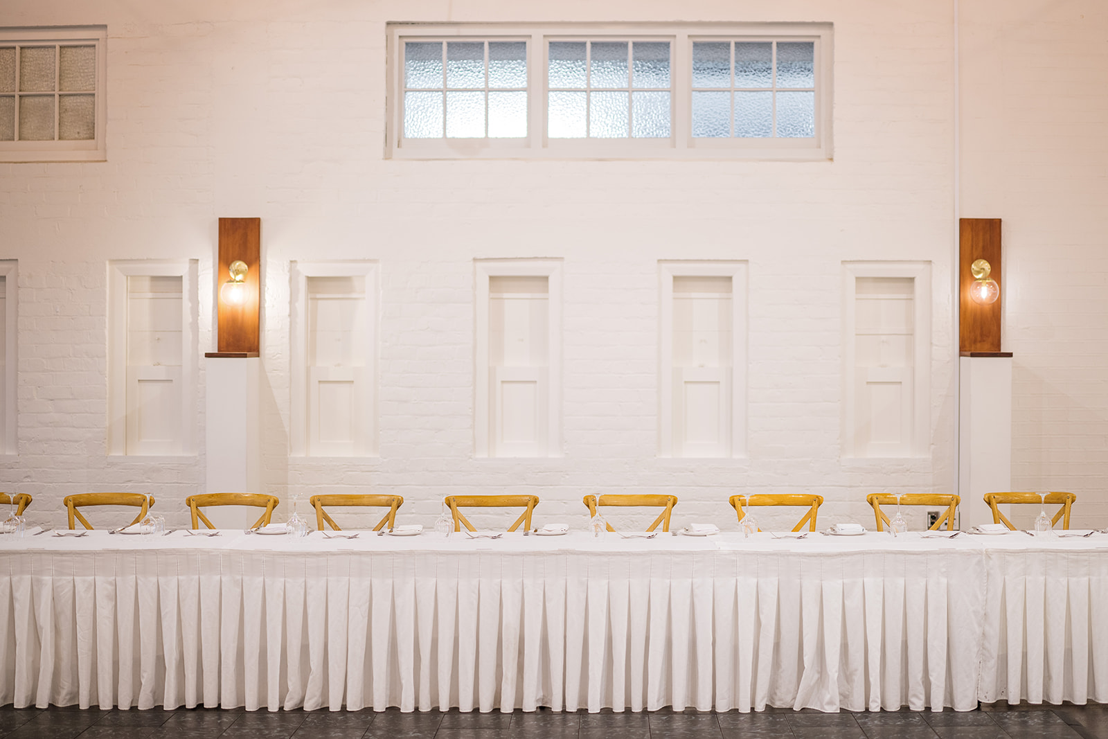 Bright white-walled function room with large windows and dining tables with guests