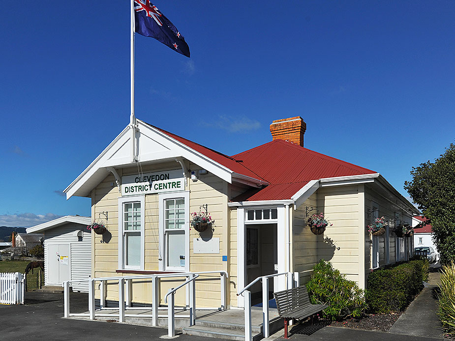Clevedon District Centre small heritage building with red roof and NZ flag