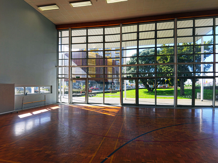 Sports hall interior with timber parquet floor and full-height glazed wall to outside