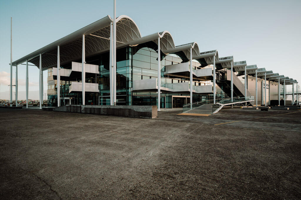 Large steel and glass event centre exterior with curved roof canopy and open forecourt