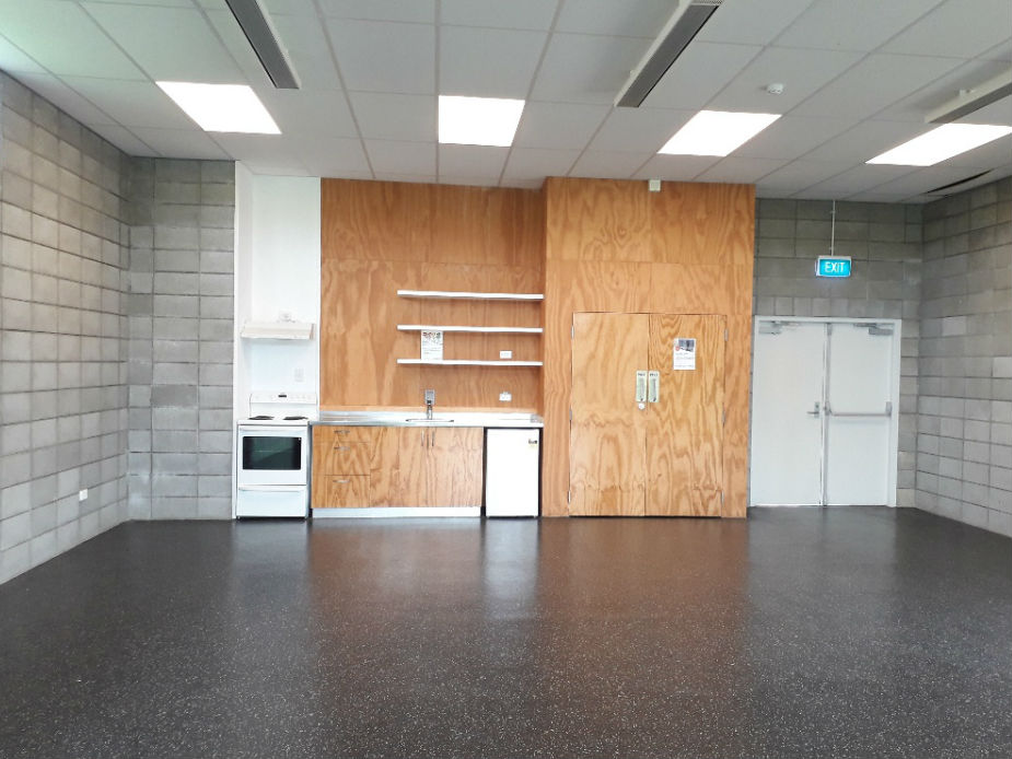 Plain hall with concrete block walls, small kitchenette, and polished floor