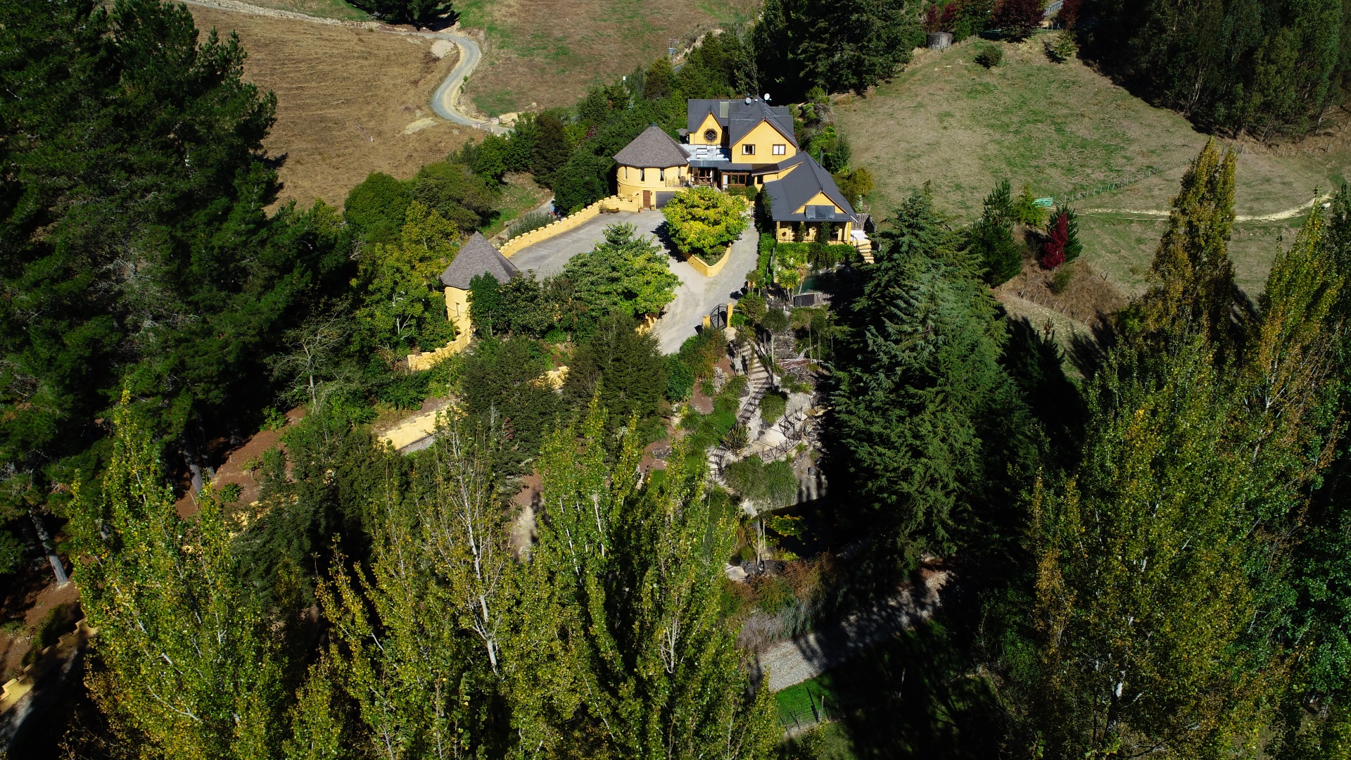 Aerial view of yellow stone castle-style building set into wooded hillside
