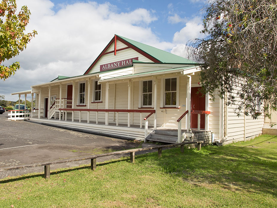 Heritage weatherboard hall with verandah, green roof, and red trim