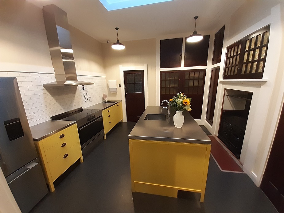 Kitchen with yellow cabinetry, island bench, and pendant lights