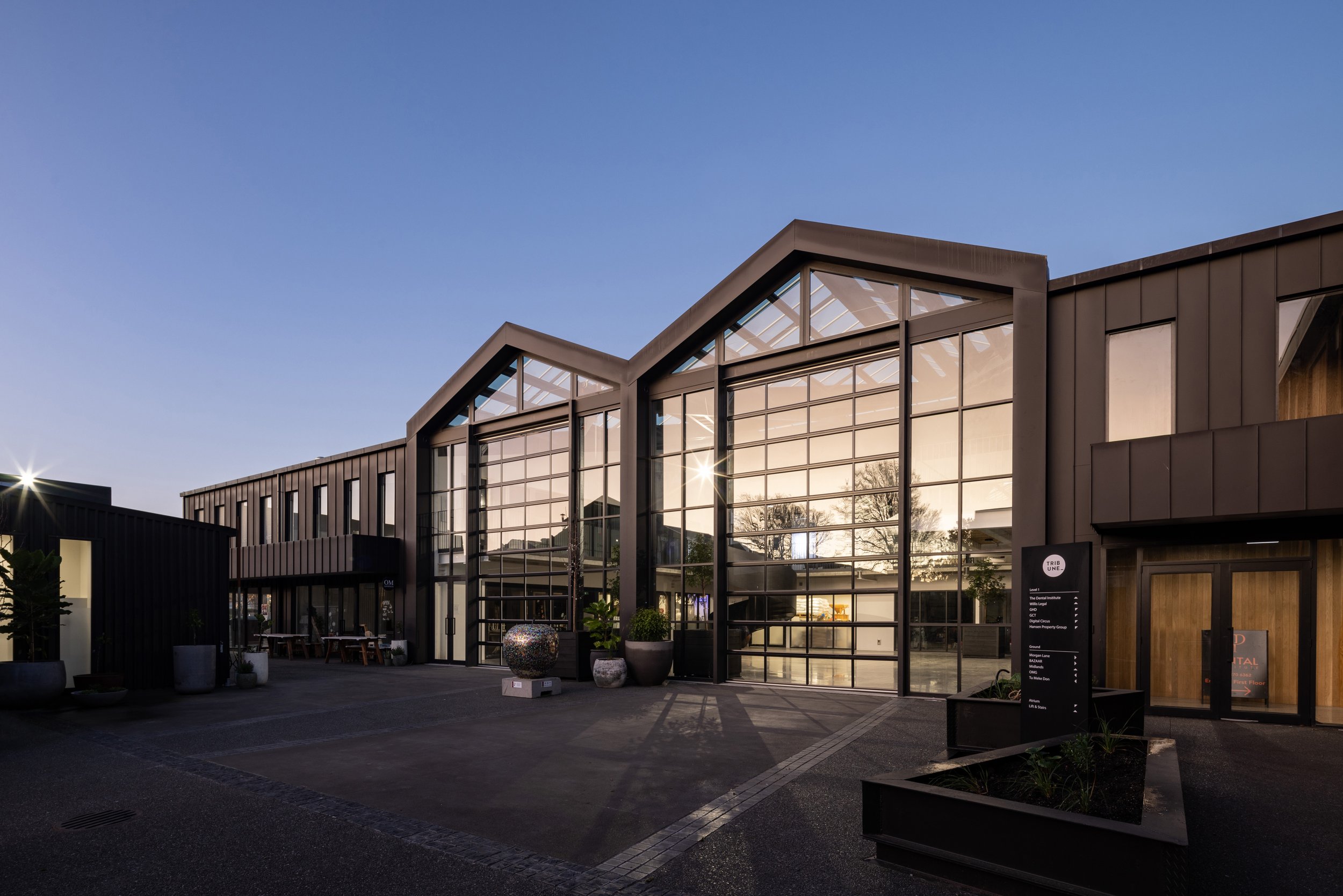 Event venue exterior at dusk, three gabled glazed facades with dark cladding