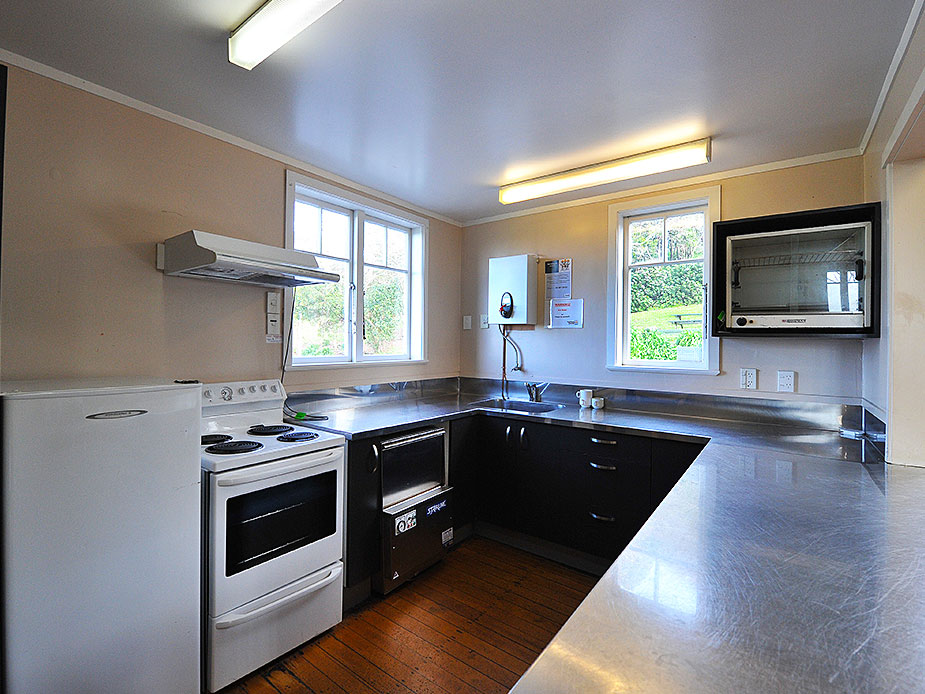 Hall kitchen with timber cabinets, stainless steel benchtops, stove and sink