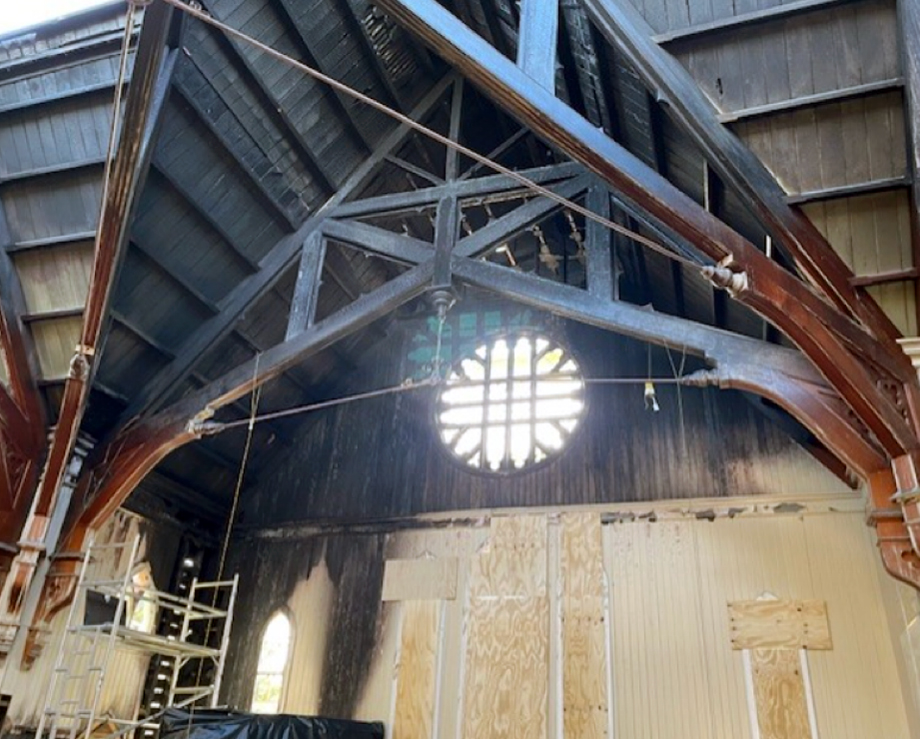 Church interior under repair with exposed timber arch trusses and rose window