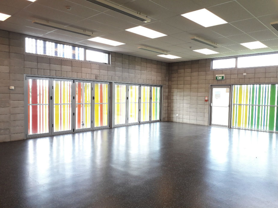 Open hall with concrete block walls, coloured glazed folding doors, and polished concrete floor