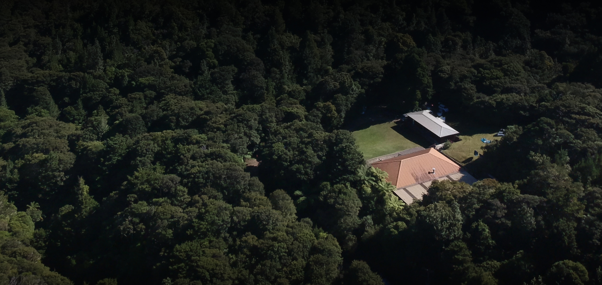 Aerial view of lodge buildings and lawn clearing surrounded by dense bush