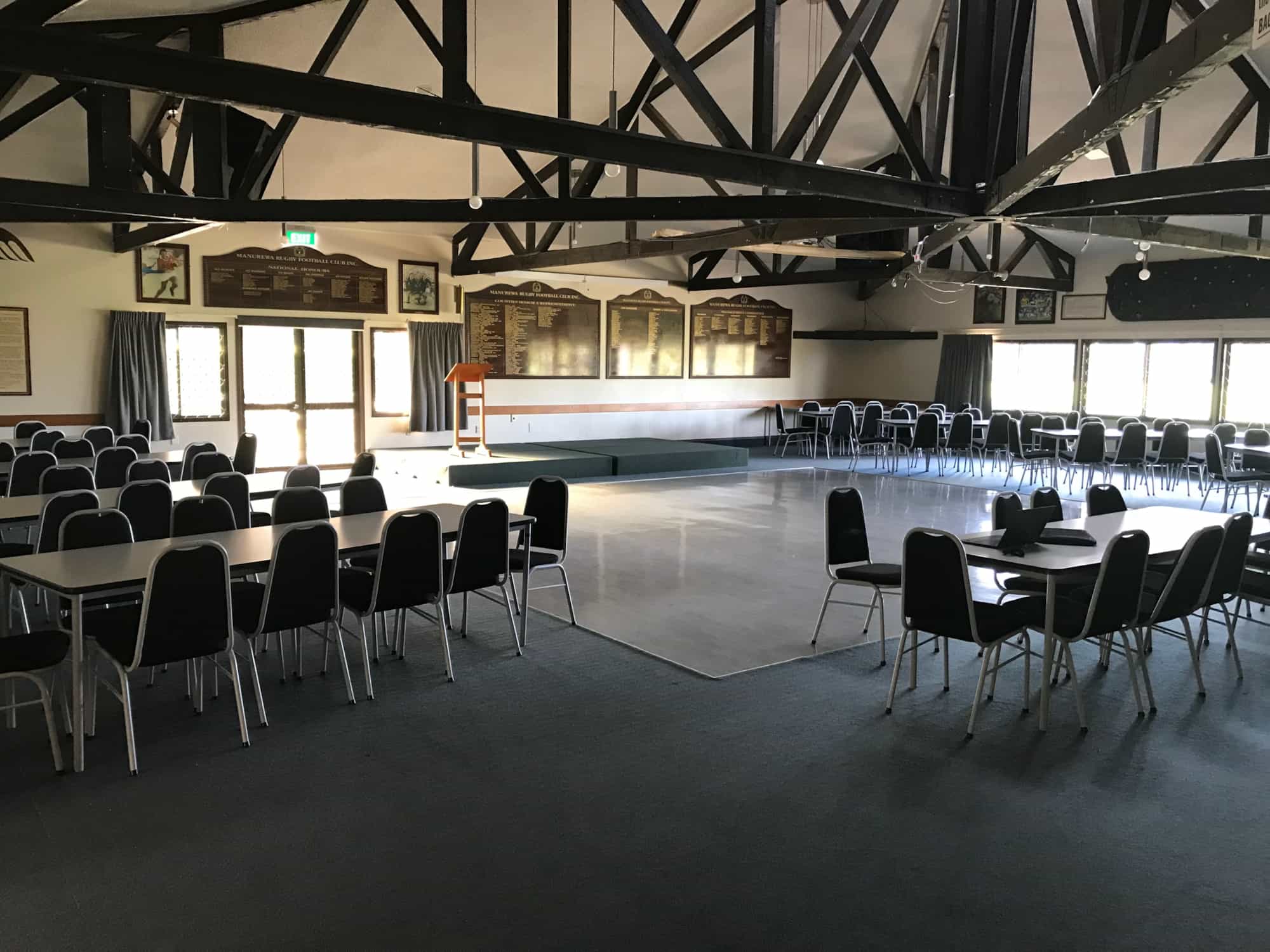 Club hall with dark timber roof trusses, tables, chairs, and honour boards on walls