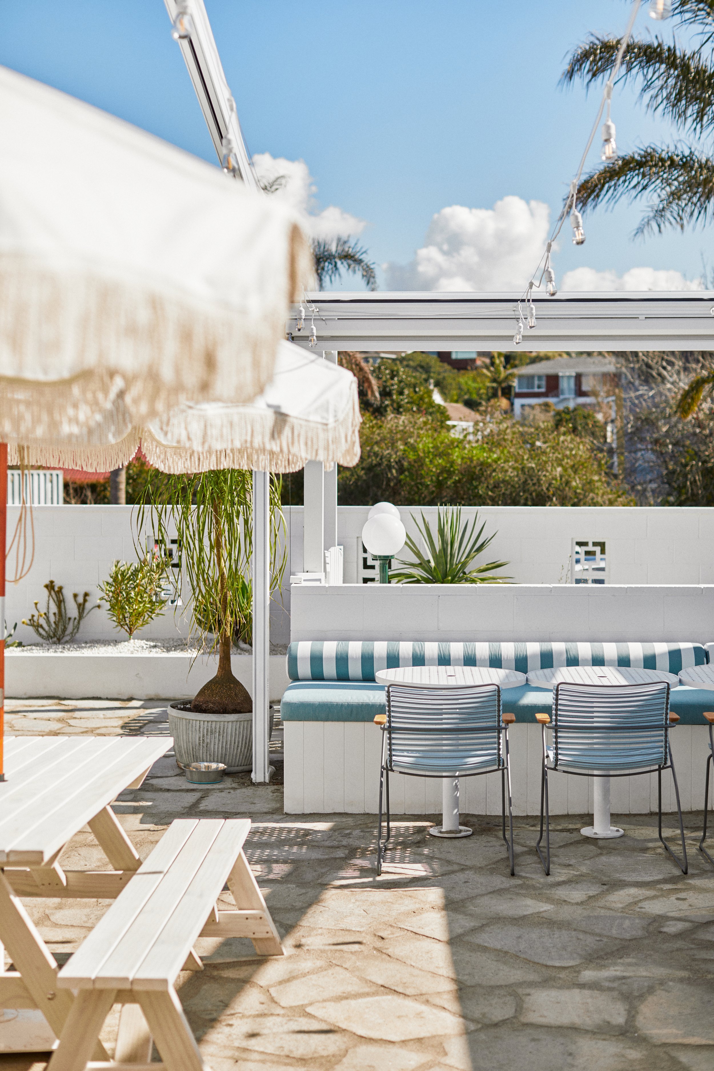 Outdoor courtyard with umbrella, bench seating and decorative neon sign on pink wall