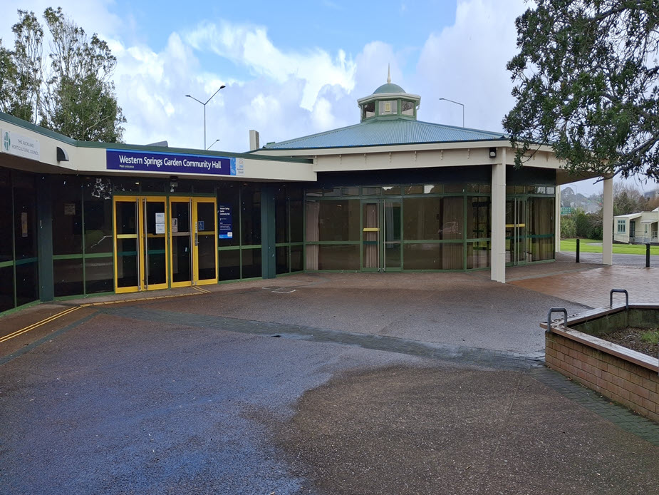 Hall frontage with green-framed glass doors, covered drop-off area, and signage