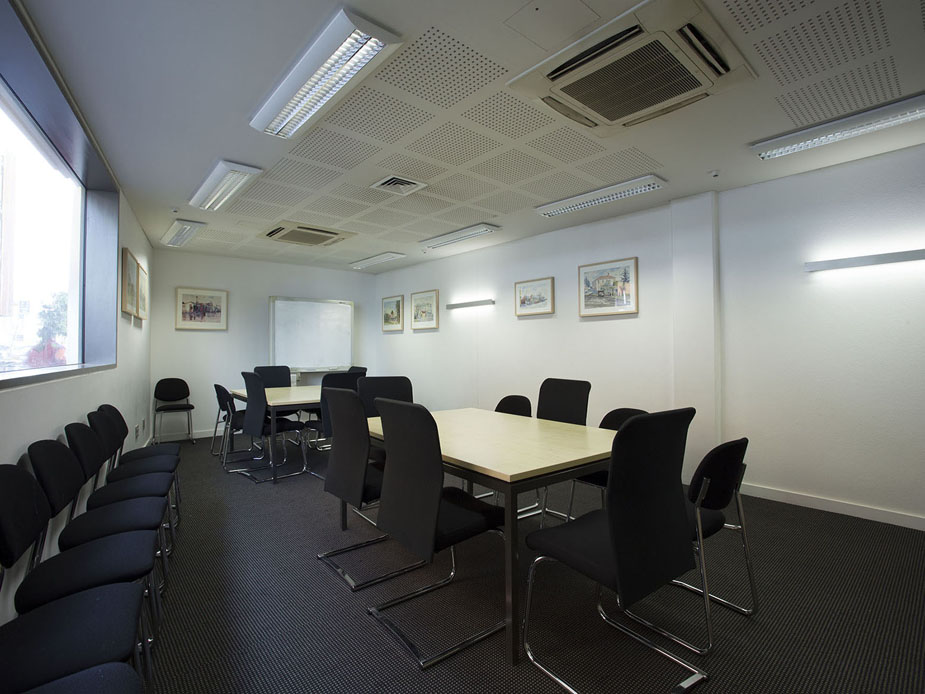 Meeting room with two sets of tables and black chairs, framed artwork on walls